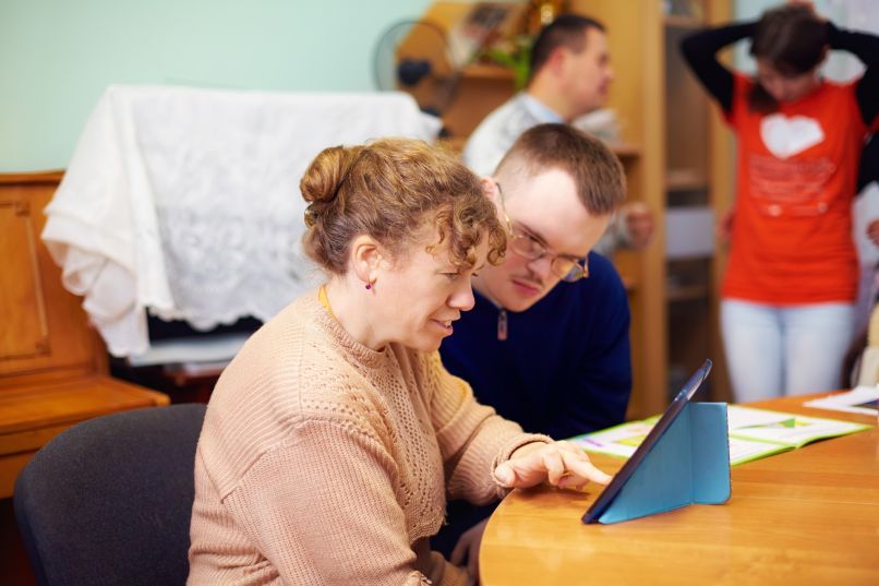 Zwei Menschen mit Behinderung arbeiten am Tablet